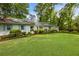 Manicured lawn and mature shrubs adorn the front yard of this charming white house at 568 Timberland Dr, Atlanta, GA 30342