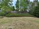 A backyard with green grass, lush green trees, and a wooden fence at 7030 Bennington Ln, Cumming, GA 30041