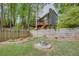 Spacious backyard featuring a wooden fence, a fire pit, lush greenery, and a multi-story home in the background at 3011 Oak Hampton Ct, Duluth, GA 30096