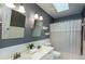 Well lit bathroom with a double sink, white cabinets, wainscoting, and a shower with a white curtain at 3011 Oak Hampton Ct, Duluth, GA 30096
