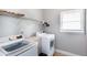 Bright laundry room featuring a modern washer and dryer set, overhead shelving, and natural light from the window at 3011 Oak Hampton Ct, Duluth, GA 30096