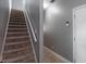 Carpeted staircase with white railings and a neutral colored wall, located next to a tile-floored hallway at 3011 Oak Hampton Ct, Duluth, GA 30096