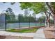 Outdoor tennis court with a tall fence surrounding the court, next to a walkway surrounded by trees at 3011 Oak Hampton Ct, Duluth, GA 30096