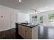 Kitchen featuring a central island with black countertop, stainless steel sink, white cabinetry, and lots of sunlight at 8475 Douglass Trl, Jonesboro, GA 30236