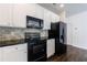 Modern kitchen boasts white cabinets, black appliances, granite countertops, and stylish backsplash at 8475 Douglass Trl, Jonesboro, GA 30236