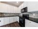 Kitchen boasts white cabinets, black appliances, granite countertops, and stylish backsplash at 8475 Douglass Trl, Jonesboro, GA 30236