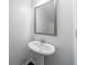 Bright powder room with a pedestal sink and modern mirror in a neutral color palette at 8475 Douglass Trl, Jonesboro, GA 30236