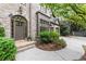 Inviting front entrance featuring a brick facade, arched doorway, lush landscaping, and elegant outdoor lighting at 3749 Watkins Ne Pl, Brookhaven, GA 30319