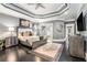 Bright, spacious main bedroom featuring a tray ceiling, modern furniture, dark wood floors and art at 1837 Miramonte Way, Lawrenceville, GA 30045