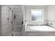 Main bathroom with soaking tub, separate glass-enclosed shower, and modern fixtures at 3728 In Bloom Way, Auburn, GA 30011