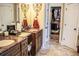 Dual sink bathroom with granite countertops, wooden cabinets, and a doorway leading to a walk-in closet at 2319 Lochinver Ln, Conyers, GA 30094
