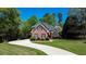 Attractive brick home features a curved driveway, manicured lawn, and mature trees, offering a serene setting at 2319 Lochinver Ln, Conyers, GA 30094