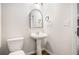 Simple bathroom featuring a pedestal sink, toilet, and an arched mirror at 859 Walking Stick Trl, Auburn, GA 30011