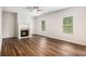 Comfortable living room showcasing a fireplace, ceiling fan, hardwood floors, and many windows at 859 Walking Stick Trl, Auburn, GA 30011