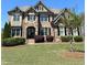 Stunning stone and brick home with manicured lawn, mature landscaping, and charming architectural details at 2671 Moon Chase Ln, Buford, GA 30519