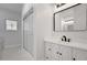 Bathroom featuring white cabinetry, a framed mirror, a tiled shower, and a decorative window at 813 Sandy Creek Rd, Fayetteville, GA 30214