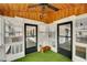 View of glass enclosed sun porch with wooden ceiling, artificial grass, and black trimmed windows and doors at 813 Sandy Creek Rd, Fayetteville, GA 30214