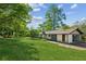 Large grassy backyard with mature trees, sunny sky, and patio adjacent to building at 4442 Mark Anthony Ct, Decatur, GA 30035