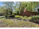 Classic brick neighborhood entrance sign with mature landscaping and an American flag under a sunny sky at 5755 Haterleigh Dr, Alpharetta, GA 30005