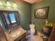 Charming powder room with a granite vanity, decorative mirror, tile flooring, and green accent wall at 5254 Franklin Goldmine Rd, Cumming, GA 30028