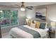 Well-lit bedroom featuring a ceiling fan, large window and a king-sized bed with decorative pillows and bedding at 5728 Norman Ct, Atlanta, GA 30349