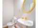 Charming half bathroom with a pedestal sink, gold-toned mirror and fixtures, plus wood-look flooring at 3819 Meandering Sw Way, Lilburn, GA 30047