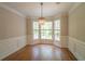 Elegant dining room with wainscoting, hardwood floors, and a chandelier with large windows at 3819 Meandering Sw Way, Lilburn, GA 30047