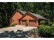 View of the brick home's exterior showcasing a two-car garage and mature landscaping surrounding the property at 5325 Pheasant Run, Stone Mountain, GA 30087