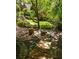 A backyard walkway leads to a cozy firepit with stone steps surrounded by greenery and shade trees at 2015 N Decatur Ne Rd, Atlanta, GA 30307