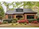 Charming brick home featuring a stone chimney, stone entryway, dormer and professionally landscaped yard with colorful flowering bushes at 2015 N Decatur Ne Rd, Atlanta, GA 30307
