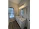 Bright bathroom featuring a double sink vanity with granite countertop, decorative mirrors, and light fixture at 1703 Feast Ct, Cumming, GA 30040