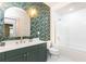 Elegant bathroom featuring a green vanity, gold fixtures, patterned wallpaper, and a shower-tub combination at 273 12Th Ne St # 114, Atlanta, GA 30309