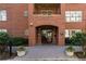 Elegant brick building entrance featuring an arched doorway, lush greenery, and a welcoming pathway at 273 12Th Ne St # 114, Atlanta, GA 30309