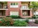 Charming red brick condo building with balconies, complemented by lush landscaping and vibrant red flowers at 273 12Th Ne St # 114, Atlanta, GA 30309