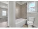 Tiled bathtub and commode in a bathroom with a window providing natural light at 1645 Dahlia Dr, Cumming, GA 30040