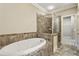 Bathroom with a large soaking tub and a separate glass-enclosed shower, tiled with neutral colors at 25 High Gate Trail, Atlanta, GA 30030