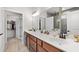 Bathroom featuring a dual sink vanity with wood cabinets, large mirror, and open doorway to the walk-in closet at 460 Marston Pass, Acworth, GA 30102