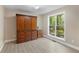 Neutral bedroom featuring wood-look floors, a large window with wooded view, and a stylish armoire at 191 Orchard Dr, Canton, GA 30115