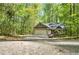 Inviting single-story home with a two-car garage, surrounded by a dense forest backdrop, accessible via a long concrete driveway at 191 Orchard Dr, Canton, GA 30115