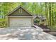 Charming residence featuring a two-car garage, lush landscaping, a welcoming walkway, and a serene wooded backdrop at 191 Orchard Dr, Canton, GA 30115