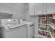 Convenient laundry room featuring modern washer and dryer, and ample storage space on shelves filled with canned food at 115 Braided Blanket Blf, Johns Creek, GA 30022