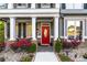 Charming front porch with stone accents, white pillars, and a vibrant red door surrounded by colorful flowers at 2582 Corey Park Dr, Loganville, GA 30052