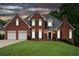 Charming brick home with a well-manicured lawn and a two-car garage at dusk at 3110 Royal Troon, Woodstock, GA 30189