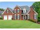 Beautiful red brick home with a 2-car garage and green lawn at 3110 Royal Troon, Woodstock, GA 30189
