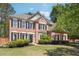 Charming two-story brick home with manicured lawn and lush landscaping creates inviting curb appeal at 715 Aronson Lake Ct, Roswell, GA 30075