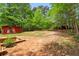 View of the large backyard, featuring red sheds and lush green trees surrounding the property at 160 Oglesby Bridge Rd, Conyers, GA 30094