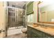 Bathroom featuring green vanity, bathtub, shower with glass door, and window with green shade at 5178 S Trimble Rd, Atlanta, GA 30342