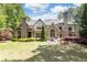 Beautiful rear exterior features stone facade, large windows, lush lawn and an outdoor seating area at 5178 S Trimble Rd, Atlanta, GA 30342