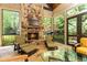 Cozy sun room with a stone fireplace, multiple seating areas, and views of the surrounding nature at 5178 S Trimble Rd, Atlanta, GA 30342
