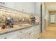Wet bar with granite countertop, mosaic backsplash, and custom white cabinetry creating a stylish entertainment space at 5178 S Trimble Rd, Atlanta, GA 30342